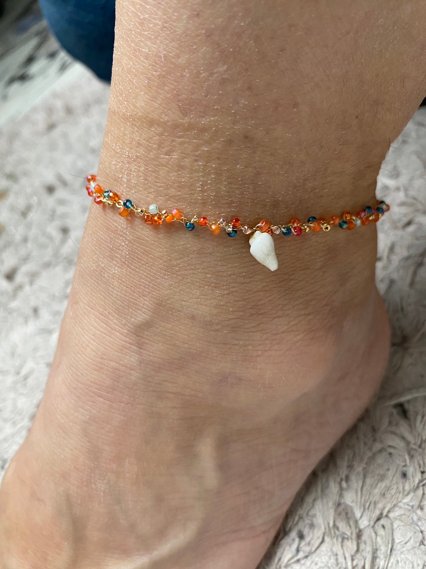 Frau trägt handgemachten gold buntes Fusskettchen mit Muschel Charm | Sabetti Schmuckdesign