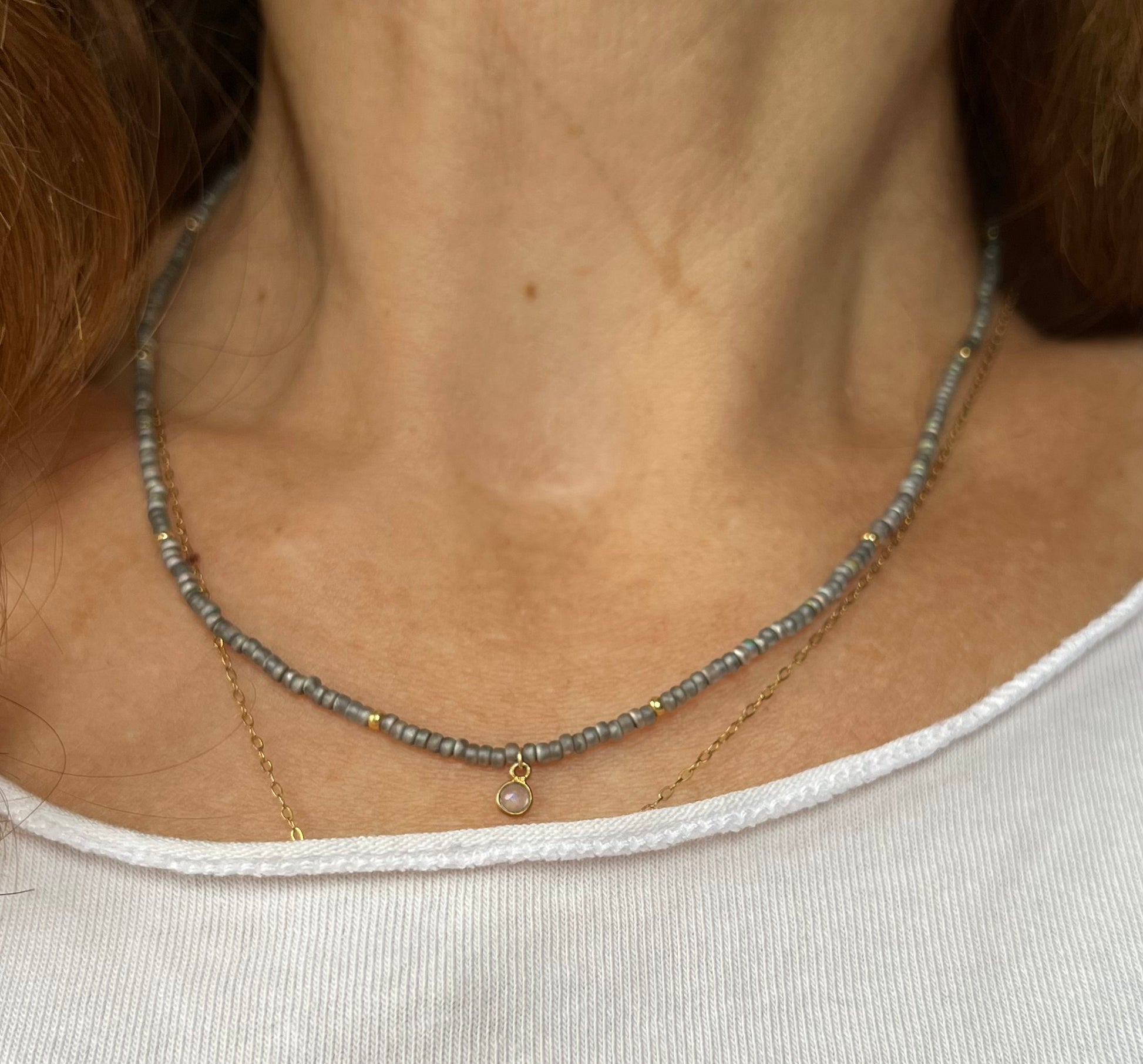 Frau trägt handgemachte feine, graue Glasperlenkette mit kleinen Labradoritanhänger